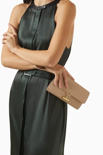 حقيبة صغيرة بحمالة معصم وغطاء قلاب بشعار حرف T جلد